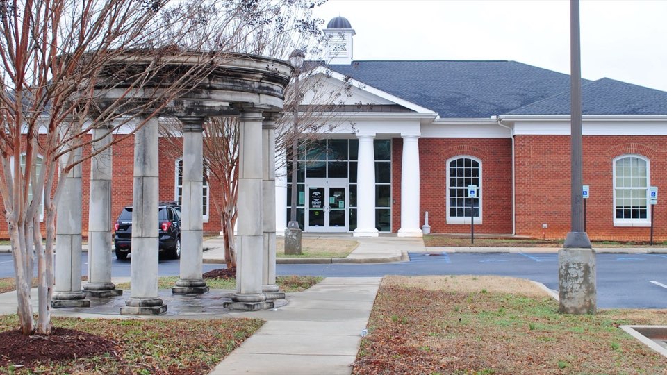 The red brick Powdersville branch library behind a stone colonnade and crepe myrtles
