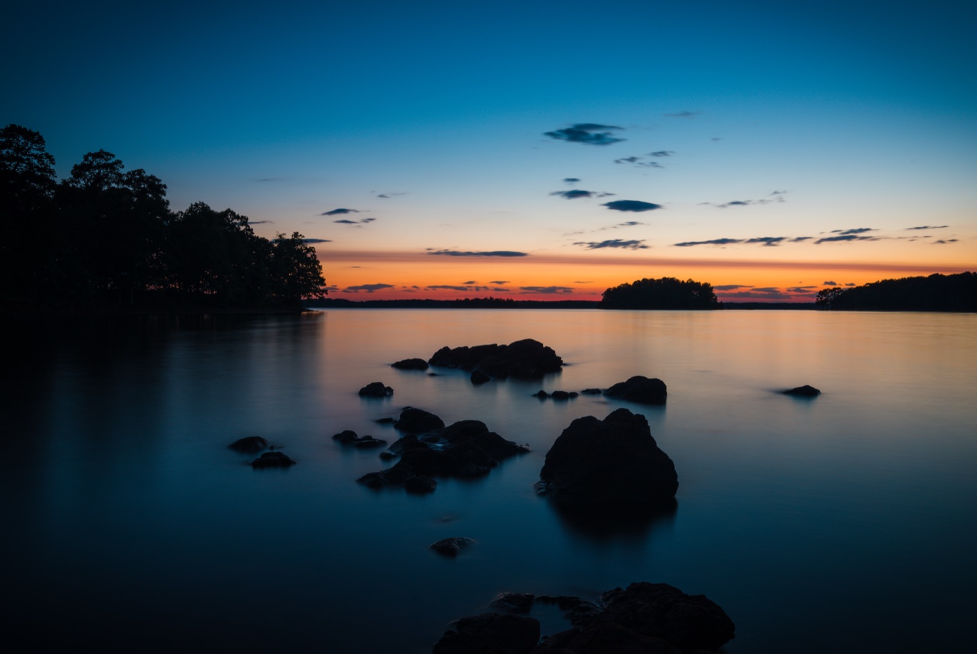 Blue hour on Lake Hartwell, silky long-exposure water around shoreline rocks under an orange horizon