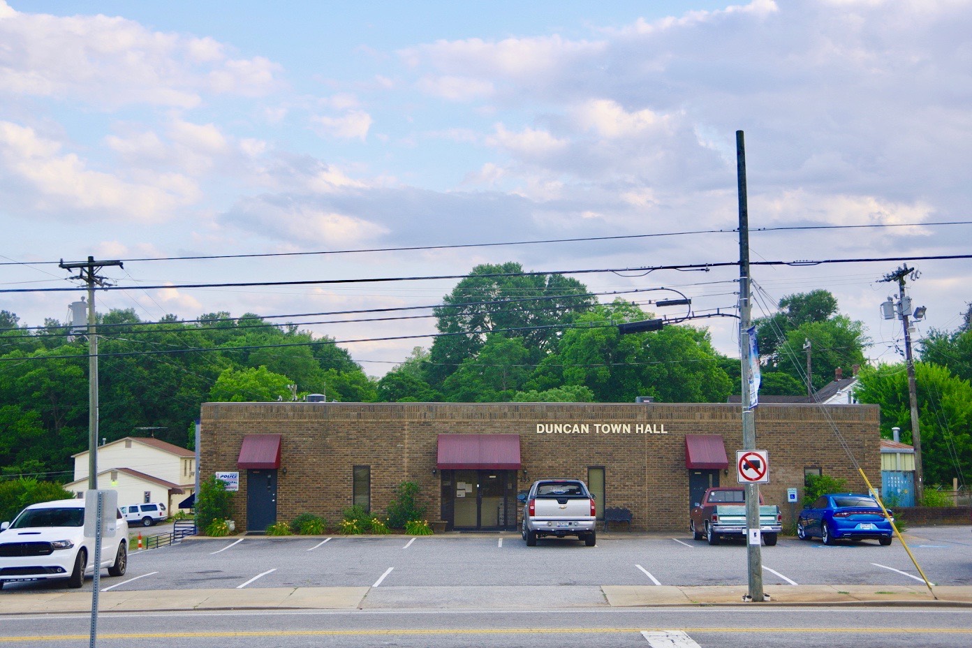 Duncan Town Hall, a low brick building with red awnings, seen across Main Street