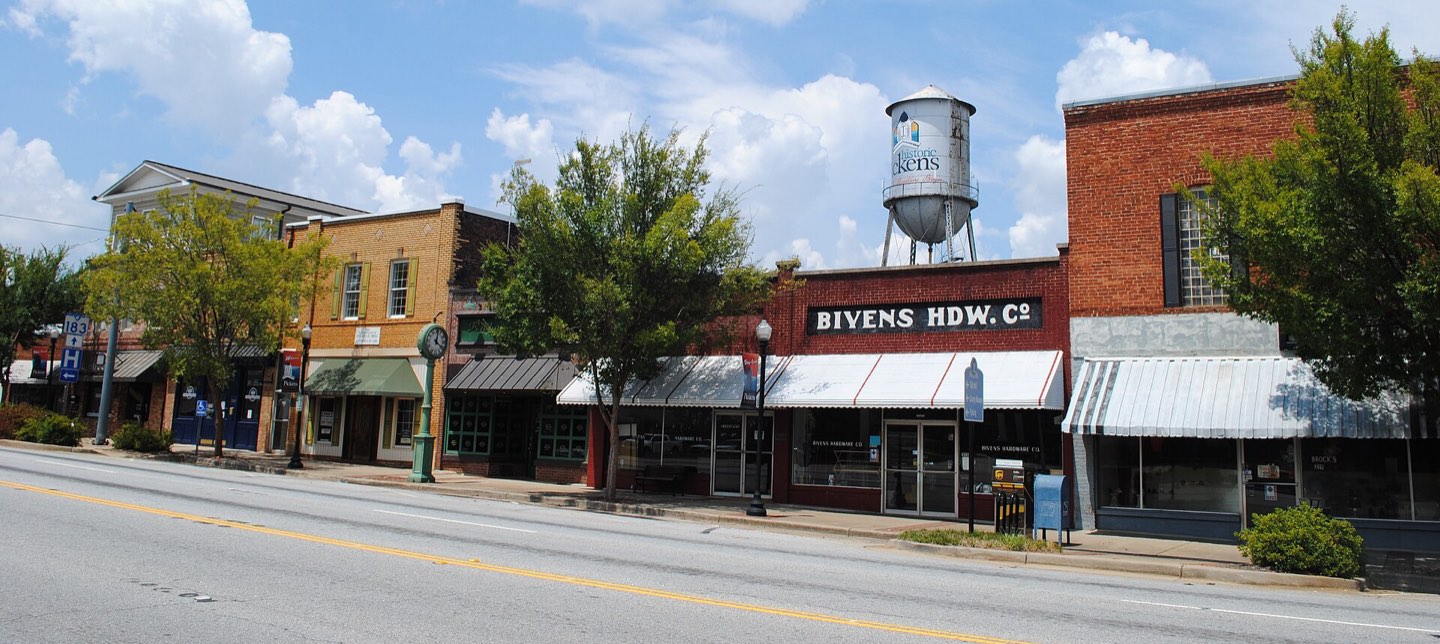 Brick storefronts along Main Street in downtown Pickens, the town water tower behind them