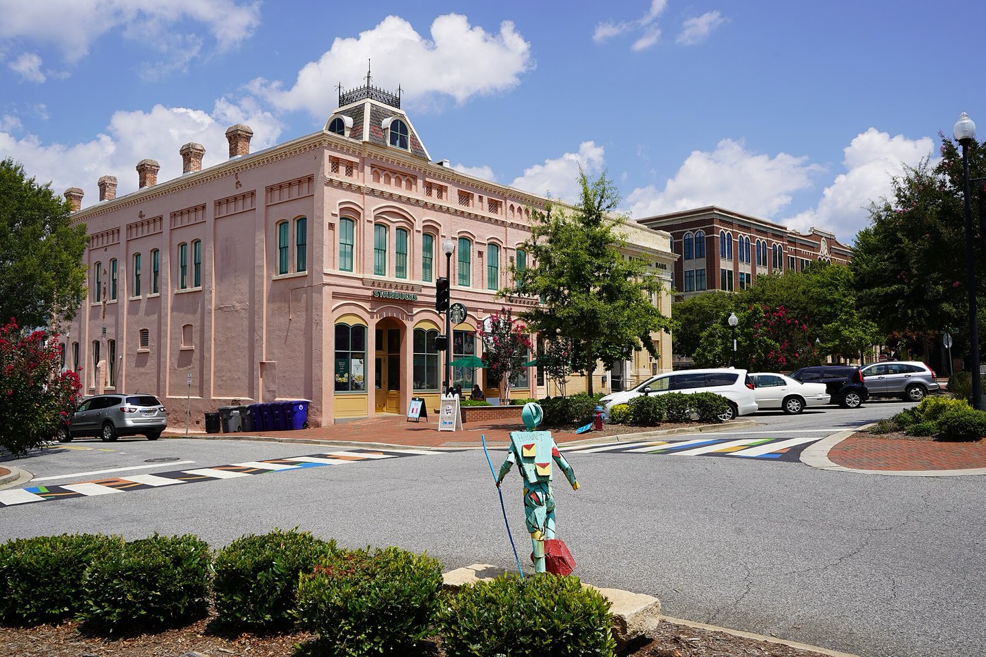 A pink brick storefront block on Main Street in downtown Spartanburg under a summer sky